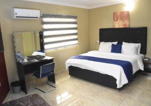 una camera da letto con un letto con una scrivania e uno specchio di 24-7 Electricity Agore Hotels and Suites Ltd a Awoyaya