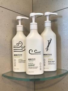 three bottles of lotion sitting on a glass shelf at Amberley Serviced Apartments in Amberley
