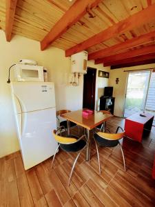 a kitchen with a table and a white refrigerator at El Diablo en Paz in Punta Del Diablo