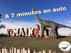 une statue de dinosaure devant un panneau dans l'établissement Studio Estrada Escobar, à Belén de Escobar