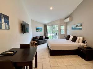 um quarto com uma cama e uma sala de estar em The Byron Beachcomber em Byron Bay