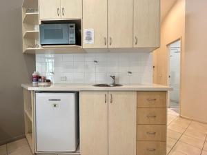 a small kitchen with a sink and a refrigerator at The Byron Beachcomber in Byron Bay