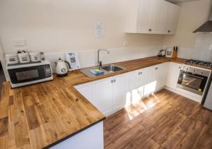 a kitchen with white cabinets and a wooden counter top at Snow Gum Apartment 1 in Baw Baw Village