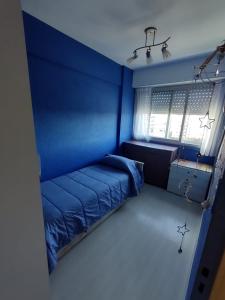 Dormitorio azul con cama y ventana en Cabo Corrientes Dueño Alquila en Mar del Plata