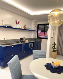 cocina con armarios azules, mesa y sillas en Conchas de Palmas, en Governador Celso Ramos