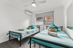 two twin beds in a room with a window at Bribie Island Canal Holiday Destination! in Bongaree