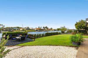 a garden with a table and chairs next to a river at Bribie Island Canal Holiday Destination! in Bongaree