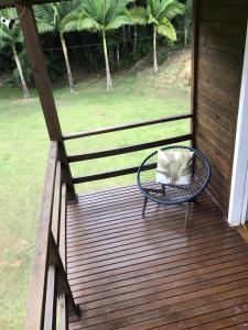 una silla de mimbre sentada en un porche de madera en Espetacular sítio com belíssima paisagem para descansar, en Cobras
