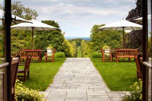 a walkway with tables and chairs and umbrellas at Lainston House in Winchester