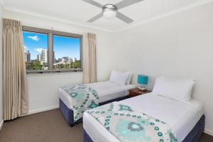 a hotel room with two beds and two windows at Rovera Apartments in Maroochydore