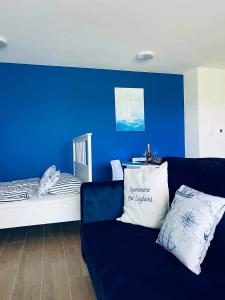 a living room with a couch and a blue wall at Apartamenty Pod Żaglami in Zegrze