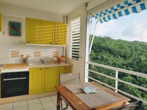 une cuisine avec des armoires jaunes, une table et une fenêtre dans l'établissement Appartement T2 Sainte Anne Caritan Melody Sunset, à Caritan
