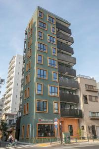 een hoog groen gebouw in een stadsstraat bij the Moto Hotel Asakusa in Tokyo