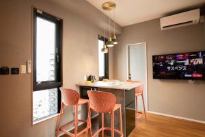 a kitchen with orange chairs and a table with a tv at the Moto Hotel Asakusa in Tokyo