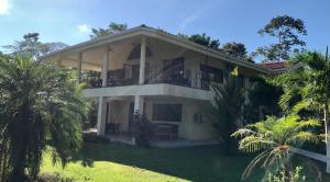 een groot wit huis met een balkon en palmbomen bij Sol y Sombra in Bocas del Toro