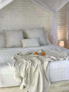 - un lit blanc avec deux oranges dans l'établissement Uluwatu Penthouse, à Uluwatu