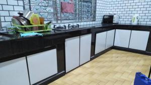 a kitchen with white cabinets and a black counter top at Cempaka Homestay Batu Pahat in Batu Pahat