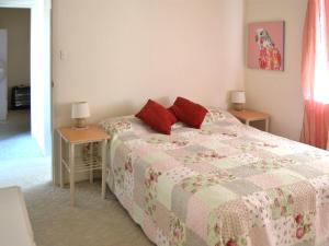 a bedroom with a bed with red pillows and two tables at Anchorage 10 in Tuncurry