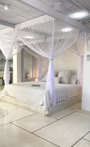 een slaapkamer met een wit bed en een baldakijn bij Uluwatu Penthouse in Uluwatu