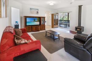 a living room with a red couch and a tv at Lakes Edge in Lakes Entrance
