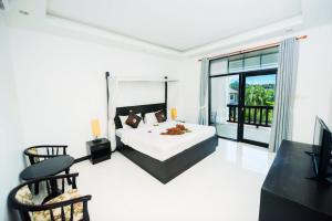 a bedroom with a bed and a large window at Monaburi Boutique Resort in Rawai Beach