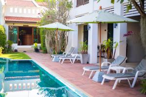a patio with chairs and umbrellas next to a pool at Monaburi Boutique Resort in Rawai Beach