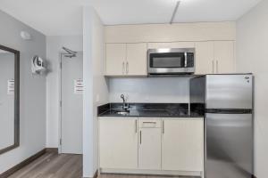 a kitchen with a stainless steel refrigerator and a microwave at Emerald Hotel & Suites Calgary Airport in Calgary
