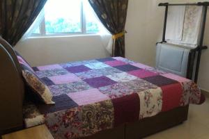 ein Schlafzimmer mit einer Decke auf einem Bett und einem Fenster in der Unterkunft MyHome 2B At Seri Kembangan With A View in Seri Kembangan