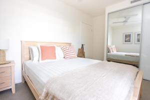 ein Schlafzimmer mit einem großen weißen Bett und einem Spiegel in der Unterkunft Dune Beachfront Apartments by Kingscliff Accommodation in Kingscliff