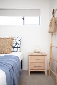 a bedroom with a bed and a wooden night stand at Dune Beachfront Apartments by Kingscliff Accommodation in Kingscliff