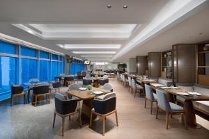 un restaurante con mesas, sillas y ventanas grandes en Ascott Xiangjiang FFC Changsha, en Changsha