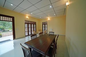 Green Haven Holiday Home في أنورادابورا: غرفة طعام مع طاولة وكراسي خشبية