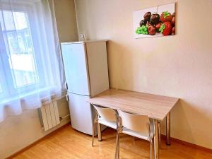 a small kitchen with a table and a refrigerator at Baikal Apartments at Vzletka - Krasnoyarsk in Krasnoyarsk