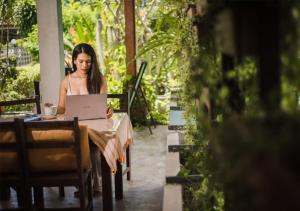 a woman sitting at a table using a laptop at Monaburi Boutique Resort in Rawai Beach