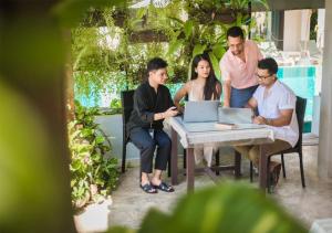 a group of people sitting around a table with a laptop at Monaburi Boutique Resort in Rawai Beach