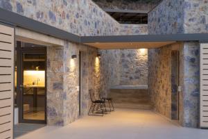a lobby with stone walls and chairs and a table at Kechria Bay Villas in Skiathos