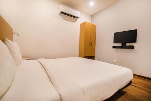 a bedroom with a white bed and a tv at FabHotel Kingston House in Lucknow