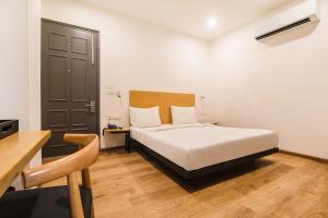 a bedroom with a white bed and a wooden floor at FabHotel Kingston House in Lucknow