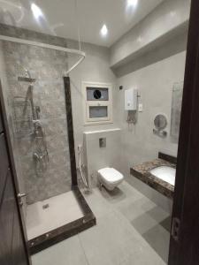 een badkamer met een douche, een toilet en een wastafel bij Eco Inn Sherook993g2 Studio in Madīnat ash Shurūq
