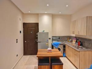 a kitchen with a refrigerator and a table in it at Eco Inn - Sherook993g2 Studio in Madīnat ash Shurūq
