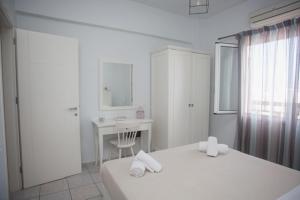 a white bedroom with two beds and a desk at Liofoto Sea View Apartments in Stalida