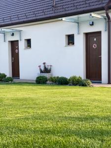 フェルテーラーコシュにあるÖlyvの茶色の扉と緑の芝生の白い建物