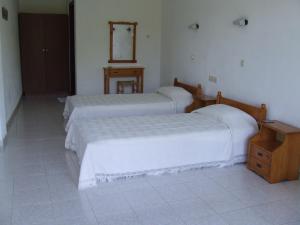 a bedroom with two beds and a wooden table at Dawn's Rooms in Patitiri