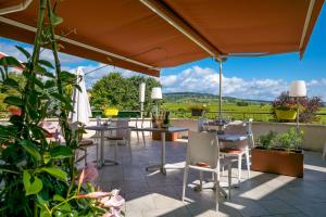 eine Terrasse mit Tischen, Stühlen und Pflanzen in der Unterkunft Kyriad Prestige Beaune le Panorama in Beaune