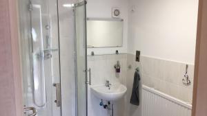 a white bathroom with a sink and a shower at Bungalow im Erlengrund in Rostock