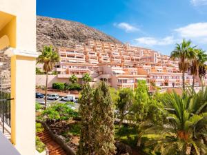 a building with palm trees in front of a mountain at 651 Bright establishment, heated pool and Wi Fi in Los Cristianos