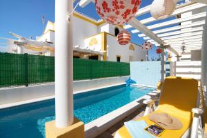 アルトゥーラにあるVilla Alagoaの建物の隣にある黄色い椅子のあるプール