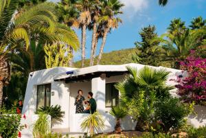 two people sitting in a small house with palm trees at Casa Munich in Ses Salines