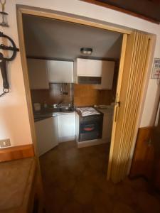 eine offene Tür zu einer Küche mit weißen Schränken in der Unterkunft Roccaraso in tasca in Roccaraso