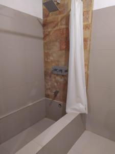 eine Dusche mit einem weißen Duschvorhang im Bad in der Unterkunft Ocean Resort Amed in Amed